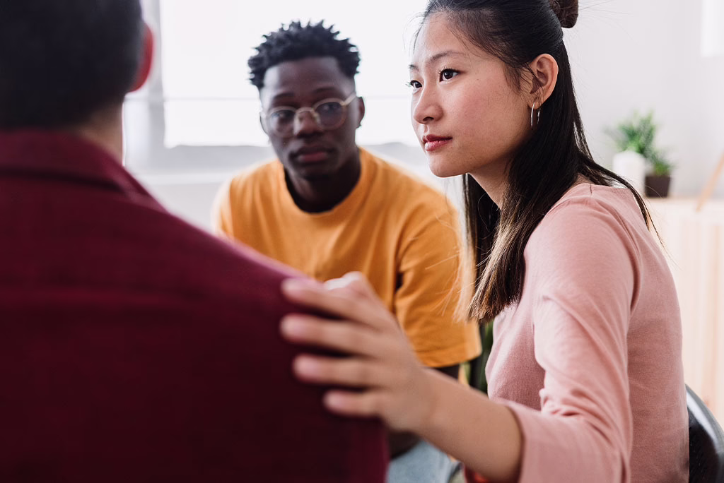 Female clinician comforting male client attending group therapy after realizing weekly therapy isn't enough